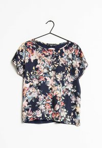 Blusa floreale a maniche corte con sfondo blu navy, caratterizzata da fiori vivaci nei colori rosa, blu e bianco. Realizzata in tessuto leggero e morbido.