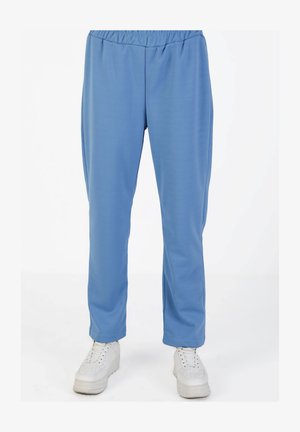 Light blue, stretchy casual pants with an elastic waistband and tapered fit, paired with white sneakers featuring textured soles.