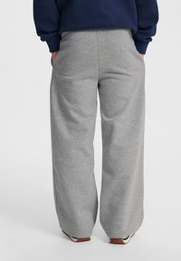 Graue Sweatpants mit einem lockeren, weit geschnittenen Design, hergestellt aus weichem Material, mit seitlichen Taschen und einer glatten Textur.