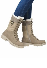 Beige all-weather laarzen met een met bont gevoerde boord, vetersluiting, zijrits, stevige zool en gestructureerde bovenkant. Voorzien van metalen accenten.