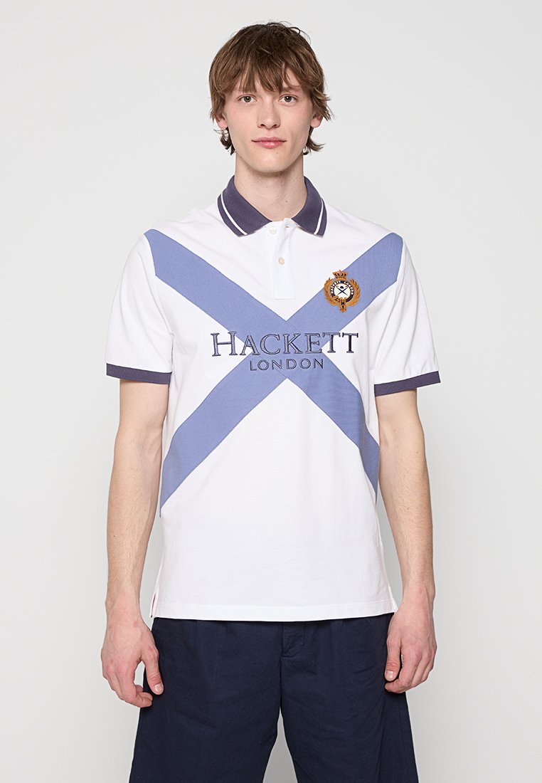 Polo blanc avec des rayures diagonales bleues, ornée d'un logo brodé. Col classique, manches courtes et ourlet droit.