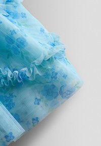 Hellblauer Tüllstoff mit Blumenmuster, verfügt über geraffte Kanten und eine weiche, transparente Textur, ideal für die Herstellung zarter Kleidungsstücke.