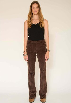 Pantalons évasés en daim marron avec une texture lisse, dotés de deux poches avant, d'une fermeture à bouton et d'une taille haute. Un débardeur noir ajusté est porté.