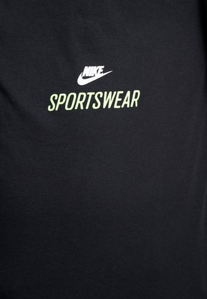 T-shirt noir en coton avec logo Nike blanc et texte "SPORTSWEAR" vert citron. Design classique à col rond, texture lisse.