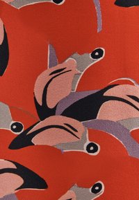 Mönstrad tyg med röda, rosa och svarta flamingomotiv på en texturerad bakgrund, med varierande former och kontrasterande färger.