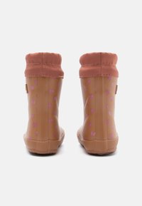 Botas de lluvia de goma marrones con un patrón de corazones rosas, que cuentan con una suela texturizada color topo y un puño de tejido suave en color rosa.