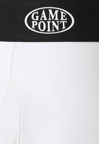 Bílé atletické šortky s černým elastickým pasem, na kterém je v oválném designu bíly text "GAME POINT". Hladká textilie.