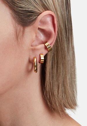 Guld metal øreringe med tre forskellige designs: en glat oval hoop, en buet stang og en tekstureret ring med tre stablede bånd.