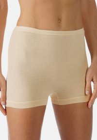 Beige bomullsblandning kalsonger med en mjuk, ribbad textur och elastisk midja. Har en skärning vid mitten av låret och inga synliga sömmar.