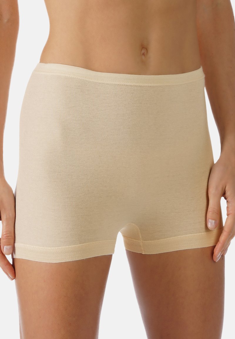 Beige bomullsblandning kalsonger med en mjuk, ribbad textur och elastisk midja. Har en skärning vid mitten av låret och inga synliga sömmar.