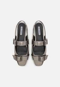 Zapatos slingback metálicos grises con punta cuadrada, que presentan una amplia correa con un acento de hebilla y un forro de tela suave.