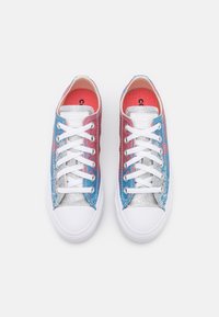 Flerfärgade sneakers med rosa, blå och silvermetalliska paneler, vita skosnören och gummisulor, med en texturerad yta.