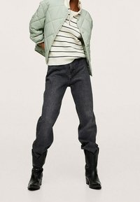 Mintgrøn quiltet jakke, hvid sweater med sorte striber, mørke denim jeans og sorte læderstøvler med spidse tå.