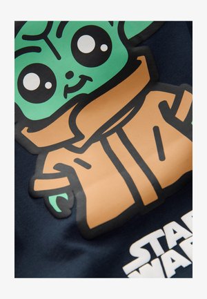 Puuvillane T-särk, millel on rohelist värvi tegelase illustratsioon pruunis rüüs, tumesinise taustal, all valge "STAR WARS" tekst.