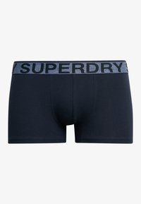 Boxer shorts bleu marine en mélange de coton doux, avec une taille élastique grise portant le texte "SUPERDRY" en noir. Détail de la poche avant présent.