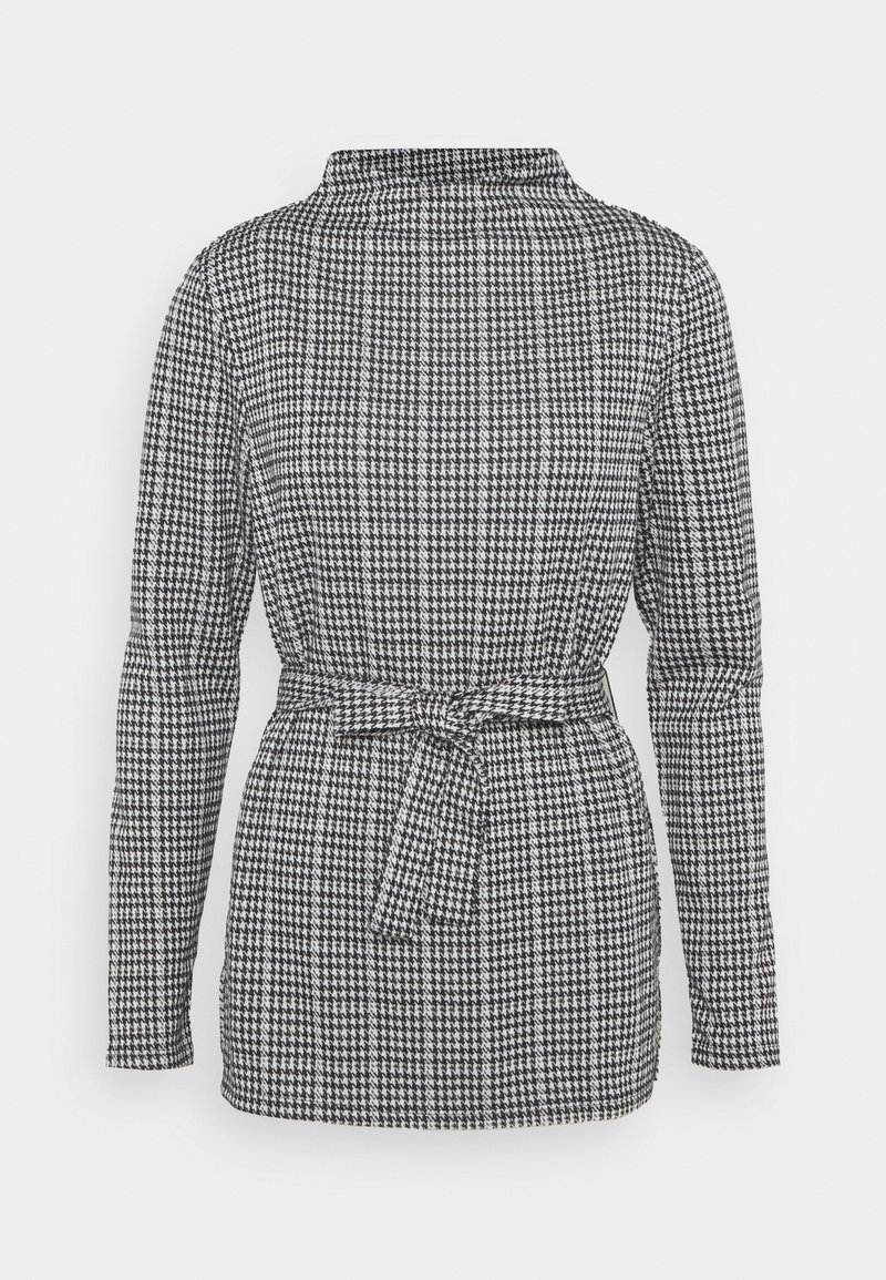 Blazer à manches longues pied-de-poule noir et blanc avec col haut et ceinture en tissu nouée à la taille, vu de dos.