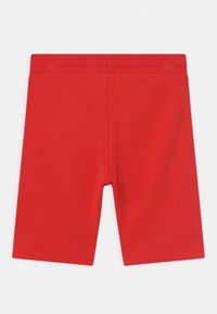 Punaiset puuvillahousut, joissa on kuminauhavyötärö, saumaton muotoilu ja sileä pinta. Housuissa ei ole taskuja tai kuvioita.