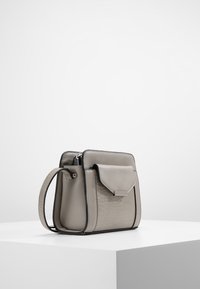 Szara torebka z ekoskóry o fakturze przypominającej skórę krokodyla, prostokątny kształt, zapięcie na zamek oraz odpinany pasek na ramię.