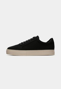Adidași negri cu un superior din țesătură netedă, având vârf rotunjit, sistem de șireturi frontal și talpă din cauciuc bej în contrast. Design minimalist.