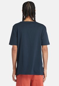 Camiseta de algodón azul marino con mangas cortas, cuello redondo y corte relajado. Presenta un sutil detalle de costura en el dobladillo y las mangas.