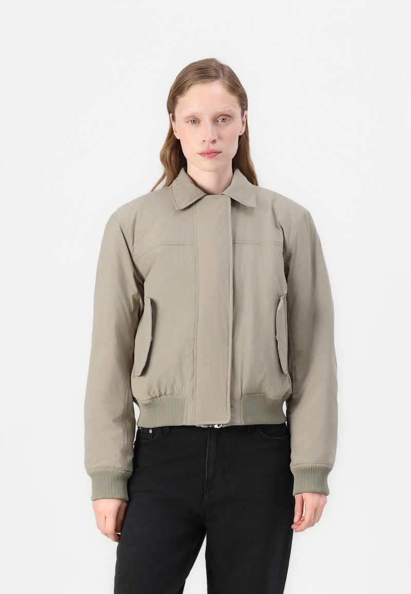 Kaki bomber jakna, s patentnim zatvaračem sprijeda, rebrasti manšeti i rub, dva bočna džepa, glatka tkanina, minimalistički dizajn, s ravnim ovratnikom.