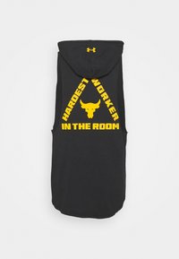 Černá bezrukávová mikina s kapucí se velkým žlutým grafickým textem "NEJTVRDŠÍ PRACOVNÍK V MÍSTNOSTI" a logem býka v trojúhelníkovém designu.