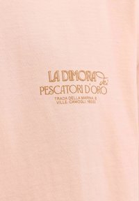 Tissu rose avec un texte doré indiquant « LA DIMORA dei PESCATORI D’ORO » et une adresse : « TRADA DELLA MARINA, 6 VILL. CAMOGLI, 16032. »