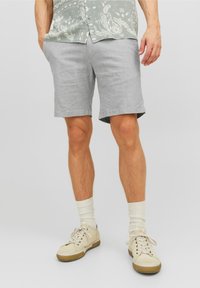 Shorts de lino gris claro con corte recto, bolsillos laterales y dobladillos enrollados, combinados con zapatillas beige y calcetines crema.