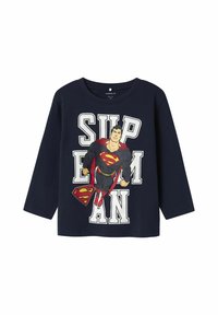 Marineblauwe T-shirt met lange mouwen met een grote Superman-graphic, voorzien van witte tekst "SUPERMAN" en rode accenten op het logo en de cape.