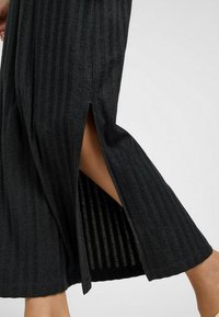 Abito midi nero a costine con aperture laterali, tessuto testurizzato e un aspetto stratificato. Il design mette in evidenza strisce verticali in tutto l'abito.