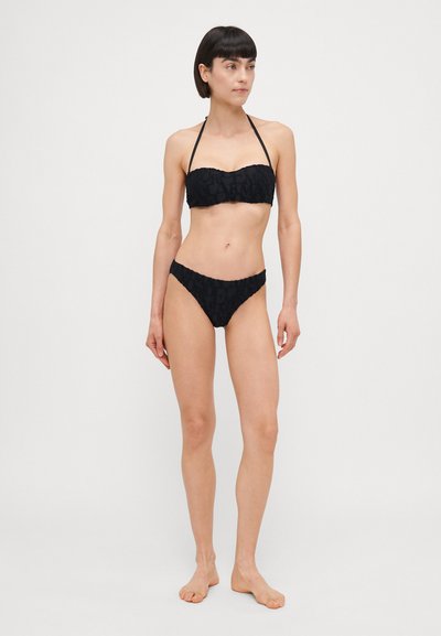 Black bikini set featuring a strapless top with ruffled edges and a textured pattern, complemented by matching low-rise bottoms.