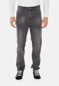 Jeans in denim grigio con una finitura sbiadita, cinque tasche e chiusura con bottone metallico. Abbinati a sneaker nere e bianche.