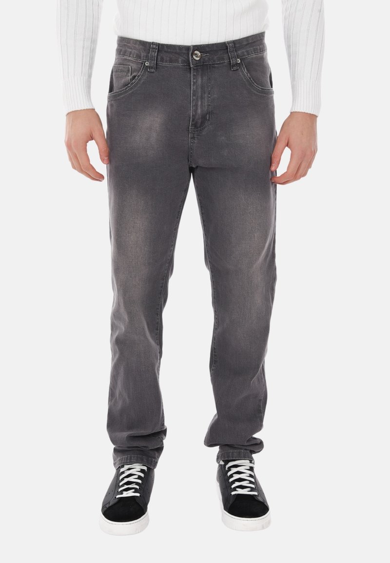 Jeans in denim grigio con una finitura sbiadita, cinque tasche e chiusura con bottone metallico. Abbinati a sneaker nere e bianche.