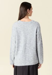 Maglione morbido di un azzurro chiaro, con una vestibilità comoda, spalle cadenti e polsini a coste. Presenta un delicato motivo testurizzato.