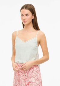 Lichtgrijze tanktop met dunne bandjes, met een scalloped halslijn, textiel met een geperforeerde structuur, gecombineerd met een rode paisley rok.
