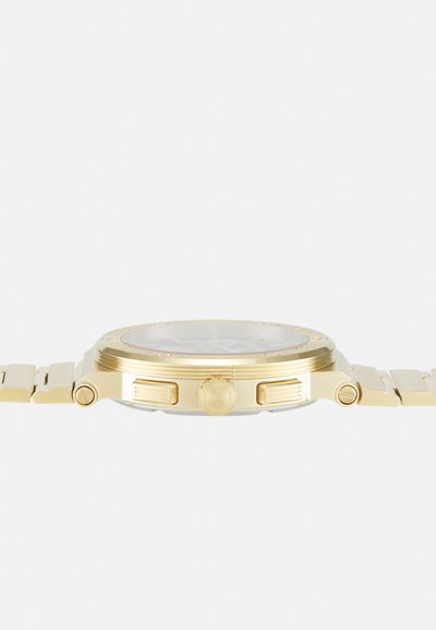 Zelta nerūsējošā tērauda pulksteņa ar apaļu korpusu, teksturētu rāmi, izteiksmīgu ķermeni un saites aproci. Skaidrs pulksteņa priekšpuse attēlo vienkāršus stundu marķierus.