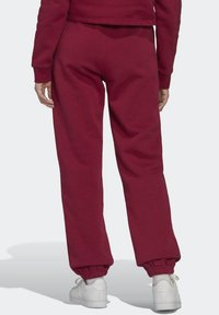 Burgundy sweatpants med elastiska muddar och midja, tillverkade av mjuk bomull, med en avslappnad passform och slät textur.