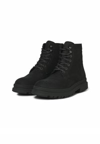 Botines de ante negro con un collar acolchado, diseño con cordones y suela de goma texturizada que presenta profundas estrías para mayor tracción.