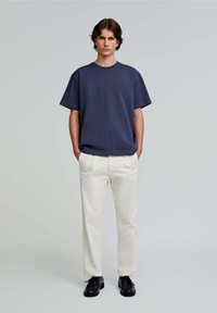 Marineblå bomulds T-shirt med afslappet pasform, parret med kridhvide chinos og sorte snørebåndssko. Simpelt design, korteærmer, ingen mønstre.