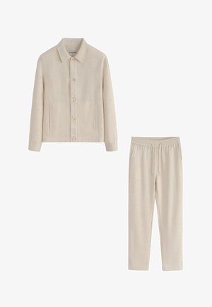 Veste beige boutonnée avec col et poches, associée à un pantalon assorti avec taille élastique et cordon de serrage.