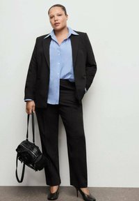 Czarny dopasowany garnitur z jasnoniebieską koszulą w paski. Czarne szpilki i mała czarna torebka. Gładkie, profesjonalne materiały.