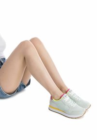 Baskets bleu clair avec des surfaces texturées, lacets blancs, et un accent rose et jaune sur le talon et la semelle. Semelle en caoutchouc avec motif.