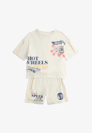 Beiges zweiteiliges Kinderoutfit mit Hot Wheels Auto- und Reifenmotiven sowie dem Text "Hot Wheels Speed Club Race" auf Oberteil und Shorts.