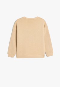 Felpa beige con collo rotondo, spalle scese e polsini a costine. Tessuto morbido e testurizzato con una vestibilità rilassata e un design pulito e semplice.