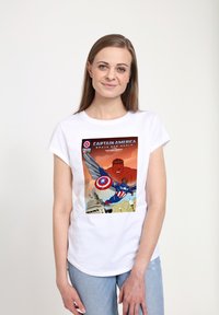 Camiseta blanca de manga corta con un gráfico colorido del Capitán América y un personaje rojo, con texto y detalles de cómic.