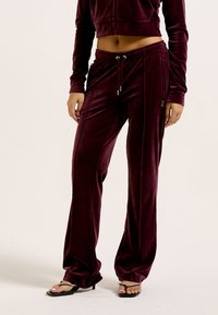Bordeaux velours trainingspak met een cropped zip-up jack en losse broek met zijzakken en een trekkoord in de taille. Soepele textuur overal.