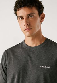 Grijze long-sleeve t-shirt gemaakt van zachte stof, met een ronde kraag en een klein wit "Pepe Jeans London" logo op de borst.