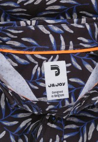 Kortärmige shirt met een marineblauwe achtergrond, voorzien van lichtblauwe en witte bladerenpatronen. Inclusief een oranje accentrand en een label met de tekst "J&JOY."