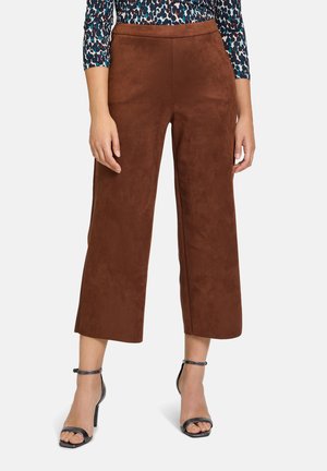 Braune Fake-Suede-Hosen mit weitem Bein und hoher Taille. Glatte Textur und klare Linien, kombiniert mit schwarzen High Heels.