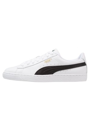 Baskets basses blanches avec détail de bande noire, fermeture à lacets et semelle texturée, vues de côté sur fond blanc.